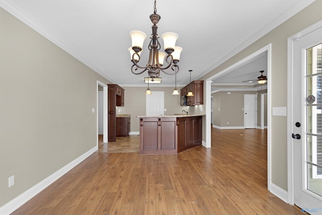 kitchen with light wood-style flooring, ornamental molding, open floor plan, a peninsula, and light countertops