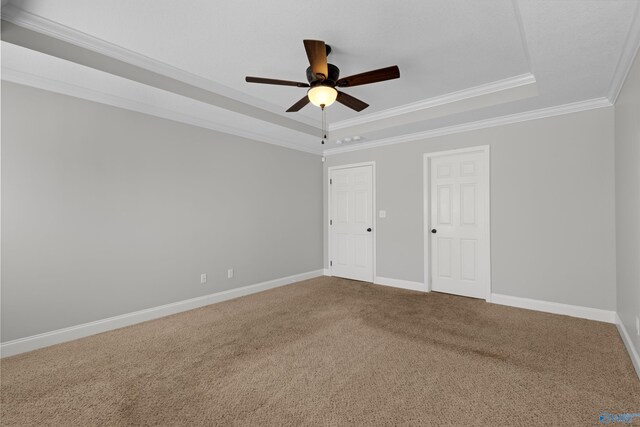 unfurnished bedroom with a raised ceiling, carpet flooring, crown molding, and baseboards