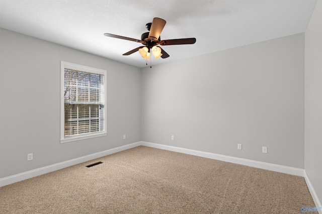 spare room with carpet floors, baseboards, visible vents, and ceiling fan