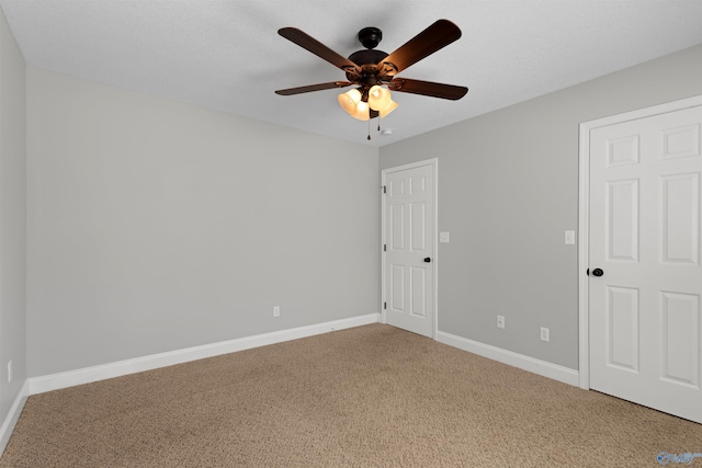 carpeted empty room with ceiling fan and baseboards