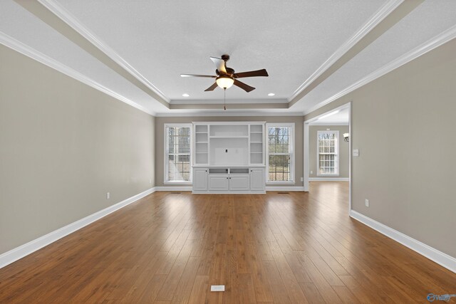 unfurnished living room featuring a tray ceiling, wood-type flooring, and baseboards