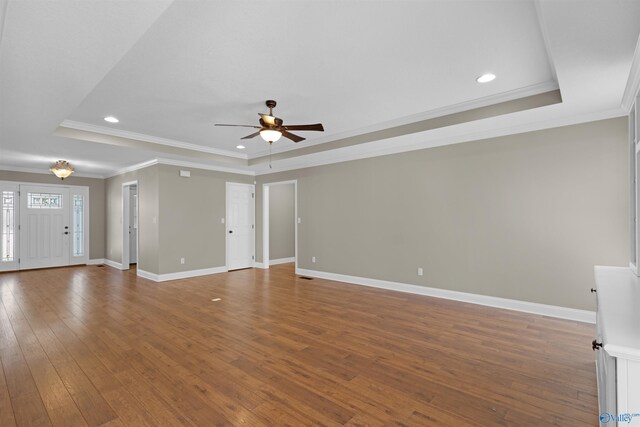 unfurnished living room with ceiling fan, baseboards, a raised ceiling, and hardwood / wood-style floors