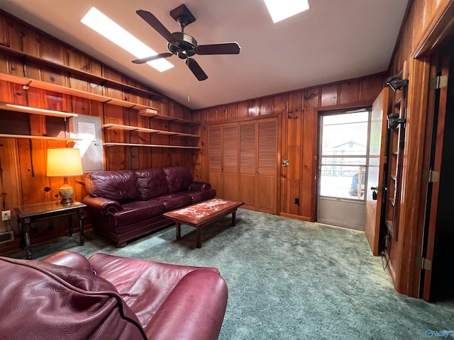 carpeted living room with ceiling fan, vaulted ceiling, and wooden walls