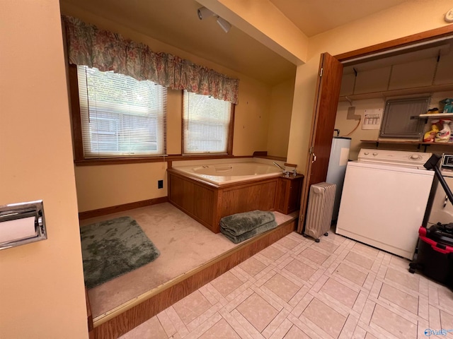 bathroom with radiator heating unit, a tub to relax in, and washer / clothes dryer