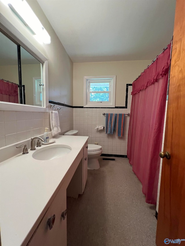 bathroom with vanity, toilet, and tile walls