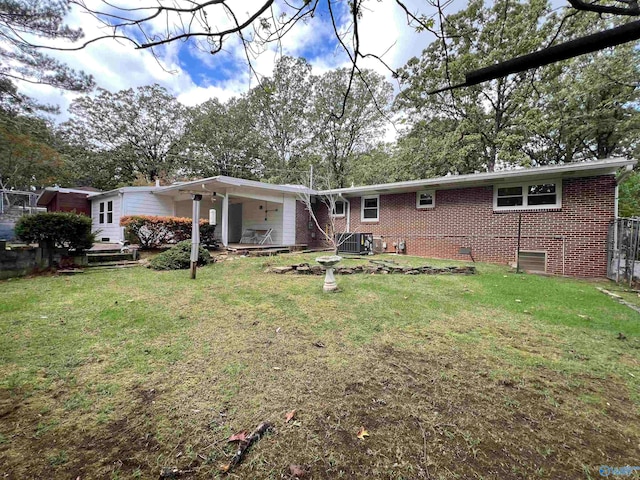 back of property with central air condition unit and a yard