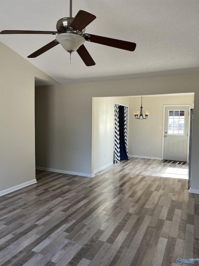 spare room with a chandelier, a textured ceiling, baseboards, and wood finished floors