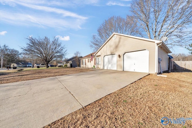 view of property exterior featuring a garage, concrete driveway, and fence