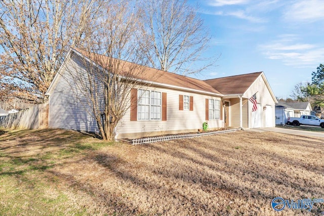 ranch-style home featuring a garage, driveway, fence, and a front lawn