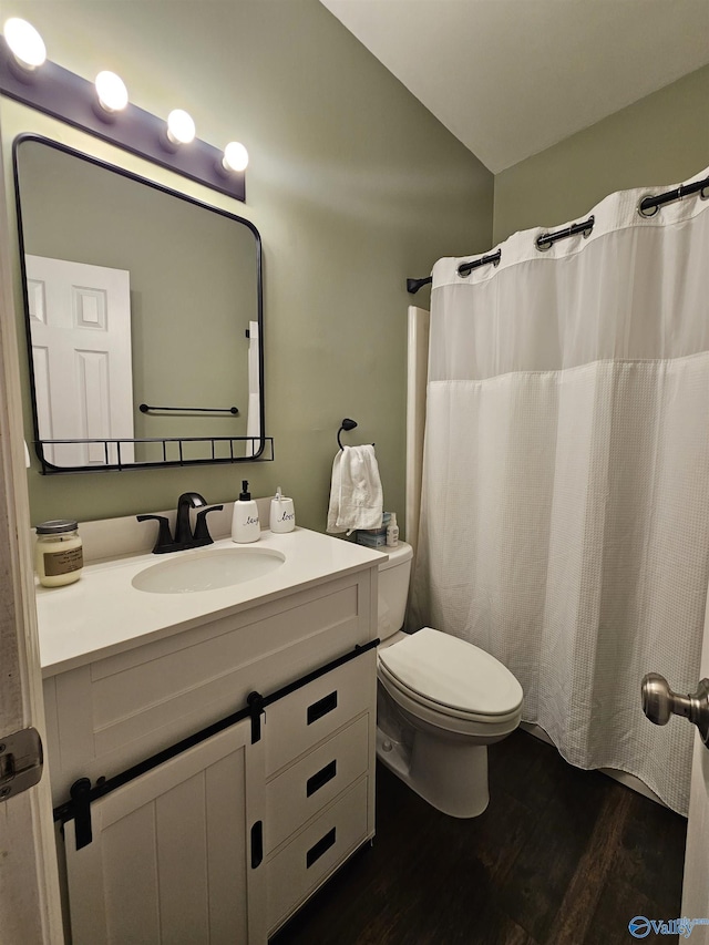 bathroom with toilet, a shower with shower curtain, wood finished floors, vanity, and vaulted ceiling