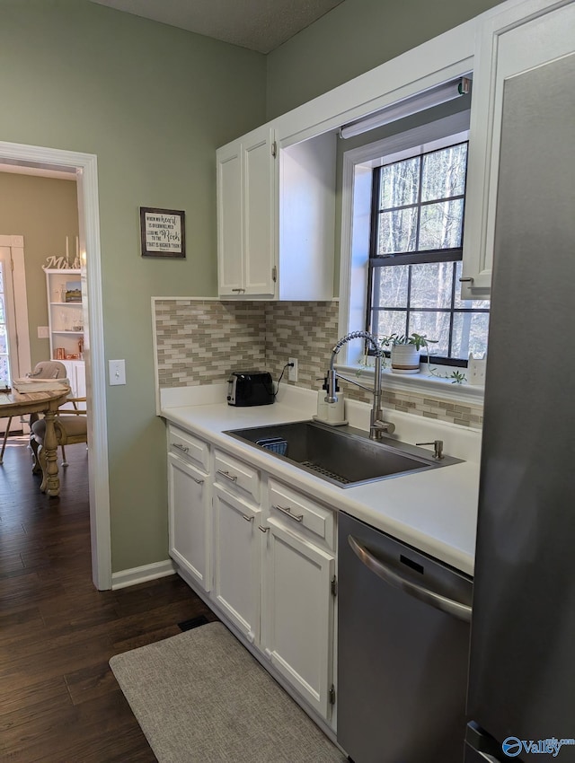 kitchen with appliances with stainless steel finishes, white cabinetry, a sink, and decorative backsplash