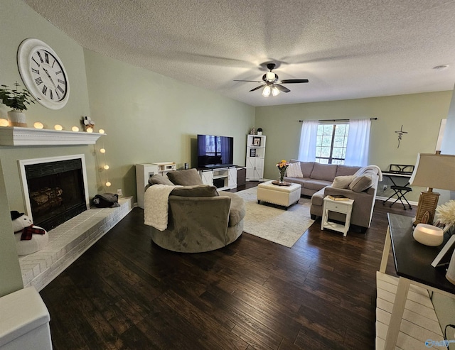 living area with a textured ceiling, a fireplace, a ceiling fan, and dark wood-type flooring