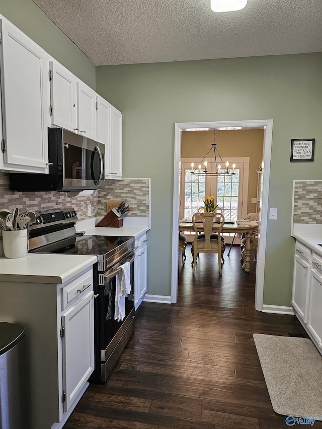 kitchen with a notable chandelier, stainless steel appliances, white cabinets, light countertops, and dark wood finished floors