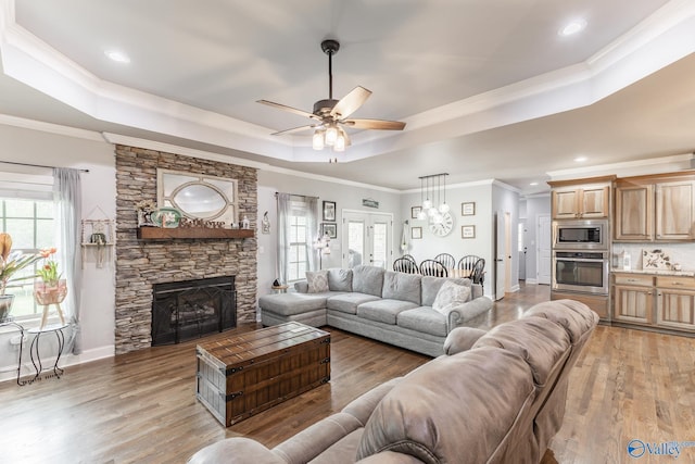 15153 Hobbs Rd, Athens, AL 35614 - living area featuring a fireplace, a tray ceiling, light wood-type flooring, a ceiling fan, and baseboards