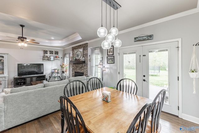15153 Hobbs Rd, Athens, AL 35614 - dining space with ceiling fan, a tray ceiling, ornamental molding, a stone fireplace, and wood finished floors