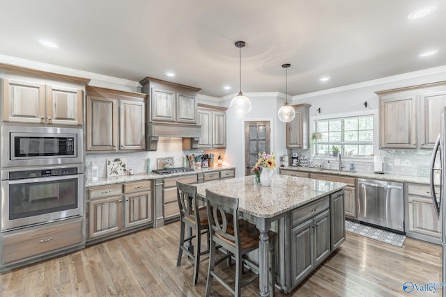 15153 Hobbs Rd, Athens, AL 35614 - kitchen featuring a sink, ornamental molding, appliances with stainless steel finishes, light wood finished floors, and a kitchen island