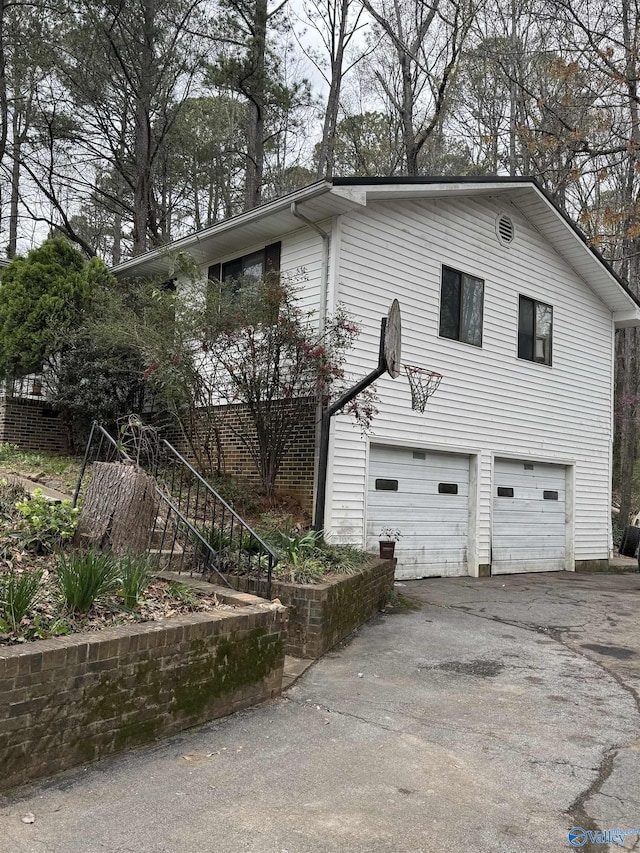 view of home's exterior with driveway, an attached garage, and stairs