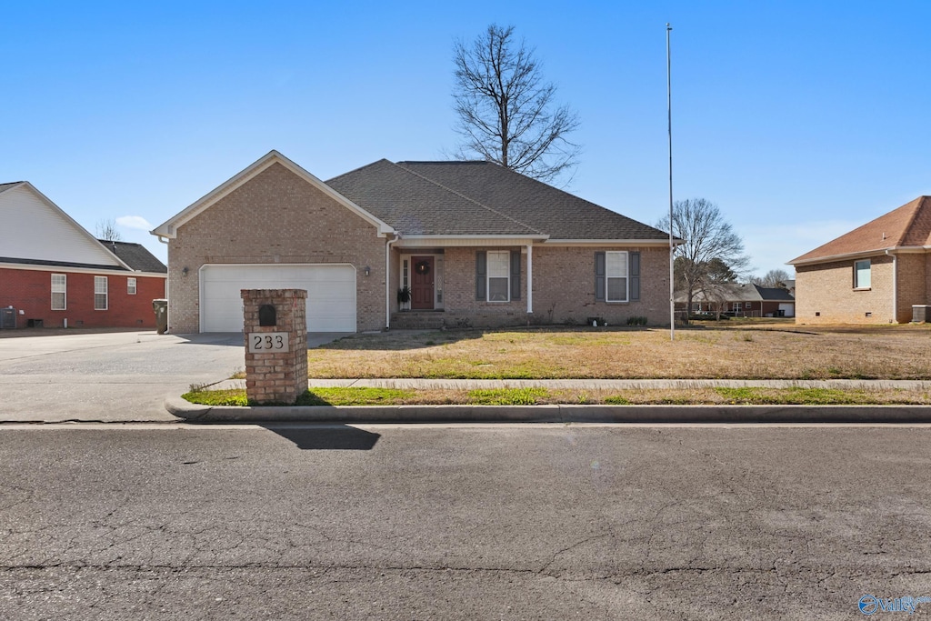 view of front of home featuring brick siding, driveway, an attached garage, and a front lawn