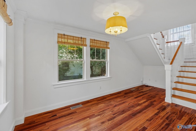 additional living space with dark wood-type flooring and an inviting chandelier