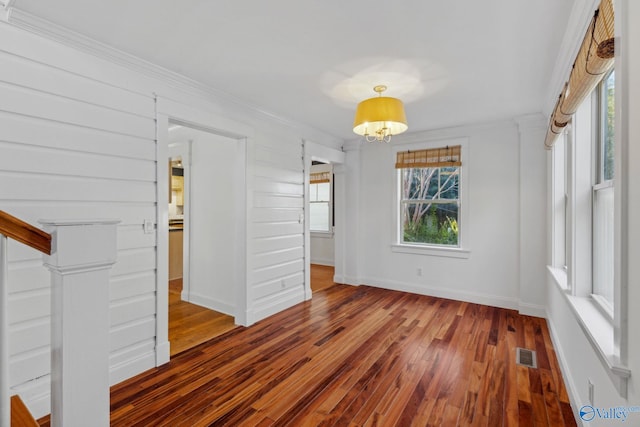 interior space featuring an inviting chandelier, crown molding, and hardwood / wood-style flooring