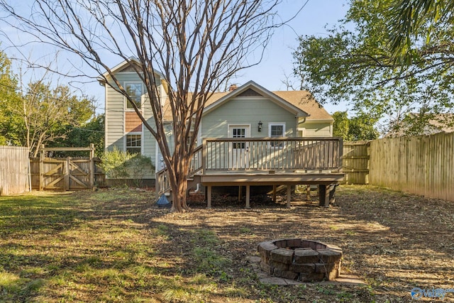 back of property with an outdoor fire pit and a wooden deck