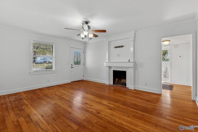 unfurnished living room featuring crown molding, a fireplace, plenty of natural light, and light hardwood / wood-style floors