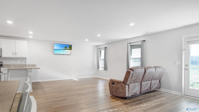 living room with baseboards, recessed lighting, and light wood-type flooring