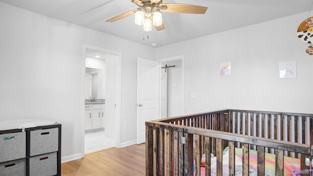 hallway with baseboards, a sink, and light wood finished floors