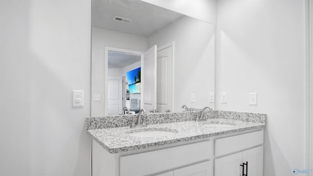 bathroom with double vanity, visible vents, and a sink
