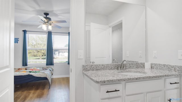 bathroom with baseboards, ceiling fan, wood finished floors, and vanity
