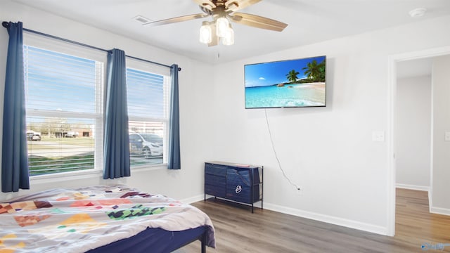 bedroom with a ceiling fan, baseboards, and wood finished floors