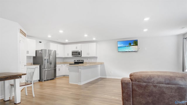 kitchen featuring light wood-style flooring, a peninsula, appliances with stainless steel finishes, white cabinetry, and open floor plan