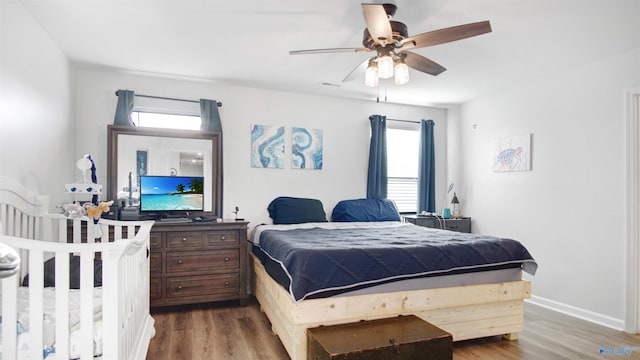 bedroom with baseboards, visible vents, ceiling fan, and wood finished floors