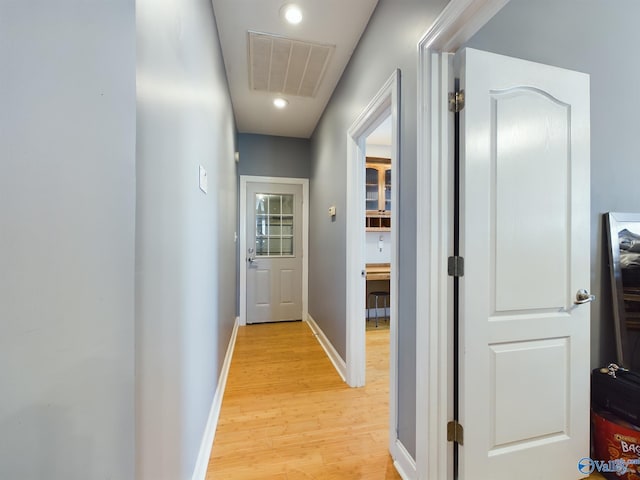 hall with light wood finished floors, baseboards, and visible vents