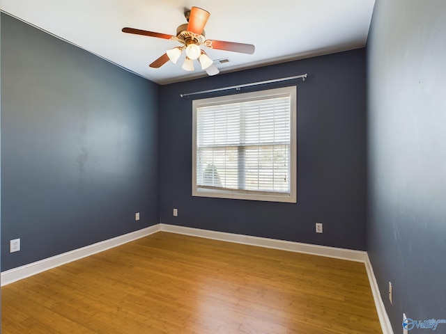 empty room with ceiling fan, baseboards, and wood finished floors