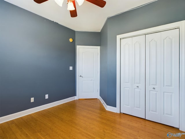 unfurnished bedroom with baseboards, a closet, a ceiling fan, and light wood-style floors