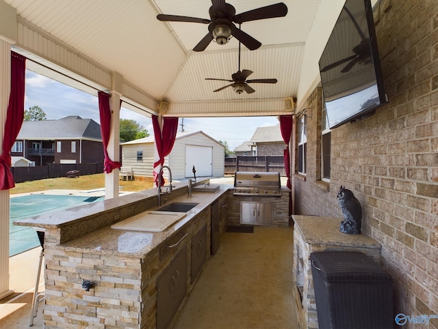 view of patio featuring an outdoor kitchen, a fenced backyard, area for grilling, a sink, and an outdoor structure