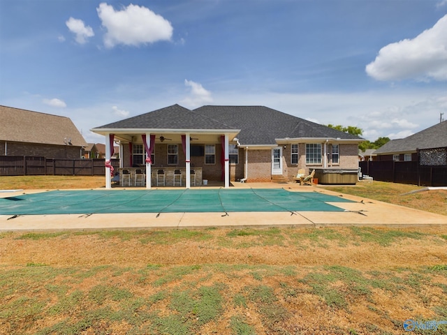 view of swimming pool featuring a hot tub, a ceiling fan, fence, a yard, and a patio area