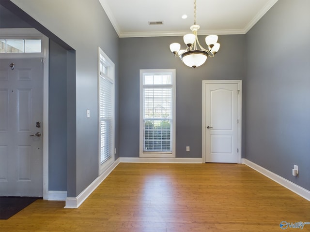 interior space featuring baseboards, visible vents, ornamental molding, wood finished floors, and a chandelier