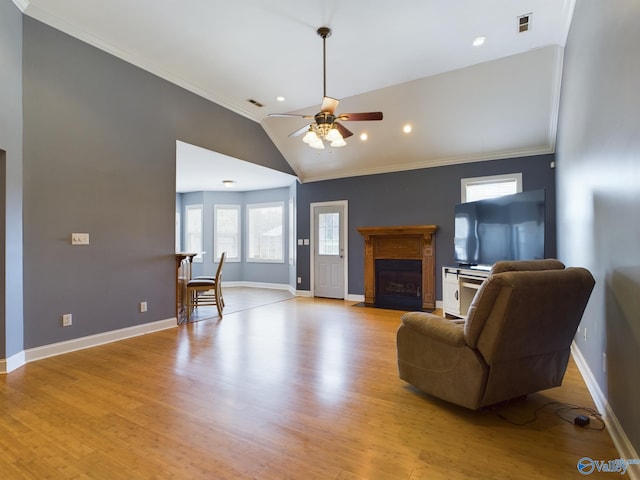 living room featuring ceiling fan, light wood-style flooring, a fireplace with flush hearth, baseboards, and vaulted ceiling