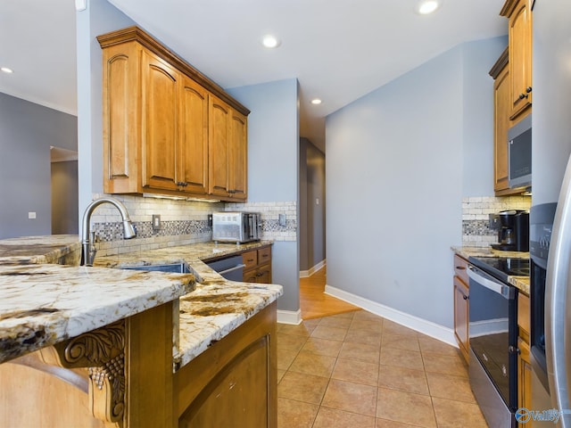 kitchen featuring baseboards, light stone countertops, stainless steel appliances, a sink, and light tile patterned flooring