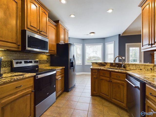 kitchen with light tile patterned floors, appliances with stainless steel finishes, a sink, a healthy amount of sunlight, and backsplash