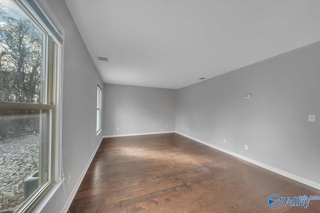 unfurnished room featuring visible vents, baseboards, and wood finished floors