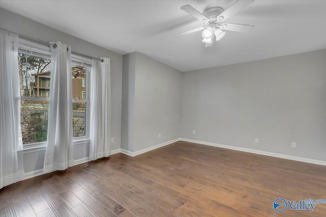 unfurnished room featuring plenty of natural light, baseboards, and wood finished floors