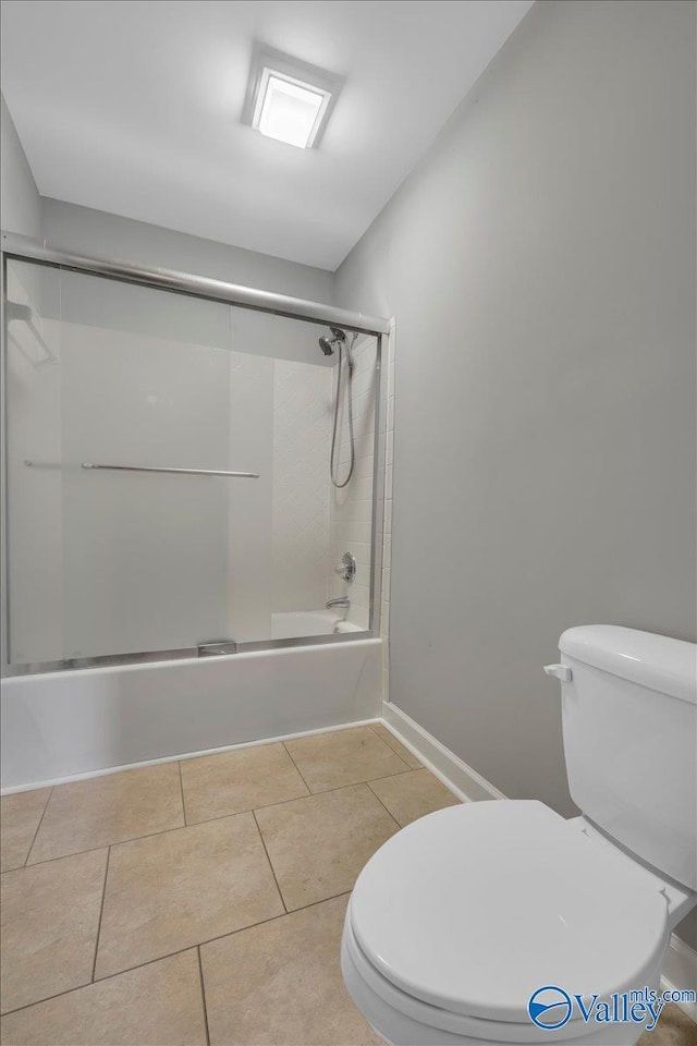 full bath featuring toilet, shower / bath combination with glass door, baseboards, and tile patterned floors