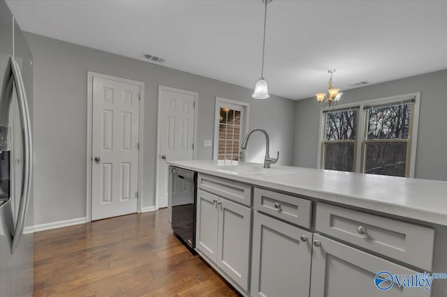 kitchen featuring a sink, visible vents, black dishwasher, dark wood-style floors, and stainless steel fridge