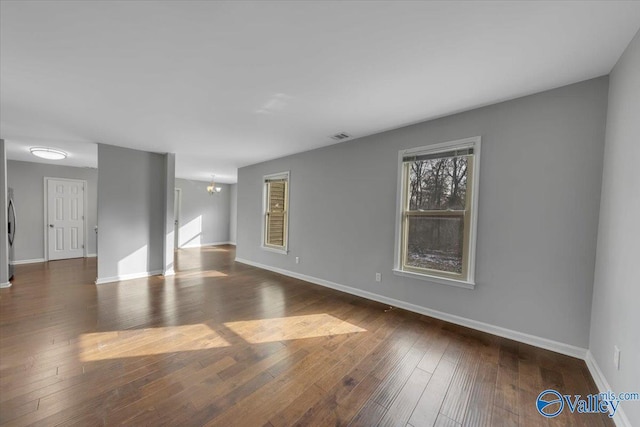 interior space featuring dark wood-style floors, baseboards, visible vents, and a chandelier