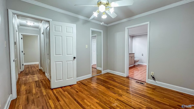 unfurnished bedroom featuring connected bathroom, hardwood / wood-style floors, ceiling fan, crown molding, and a closet