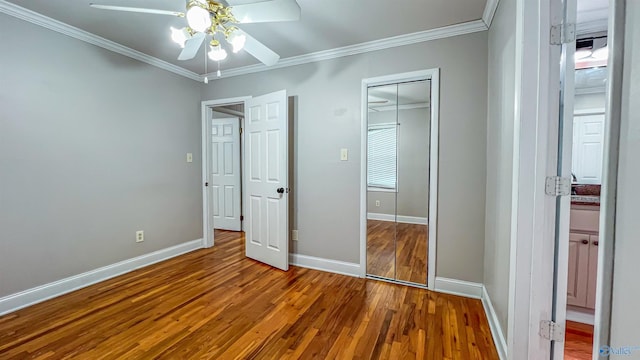 unfurnished bedroom with hardwood / wood-style flooring, ornamental molding, ceiling fan, and a closet