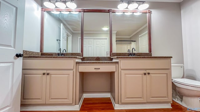 bathroom featuring ornamental molding, toilet, wood-type flooring, and vanity